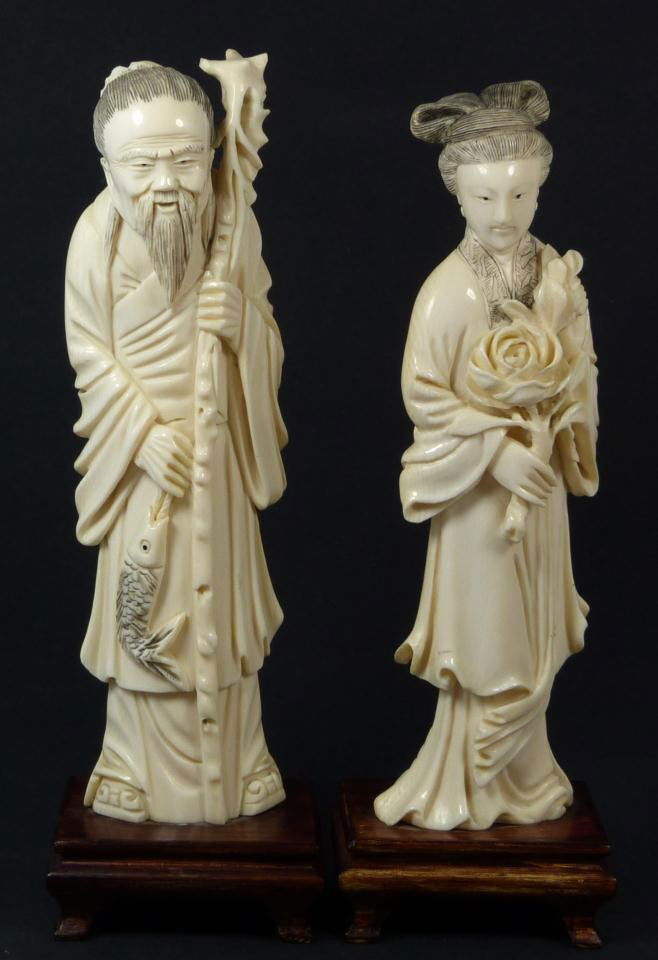 PAIR OF CHINESE CARVED IVORY MAN & WOMAN FIGURES: Two Chinese ivory hand carved figures. Depicts an old man holding wooden staff and fish. The other depicts a female holding flowers . Each has footed wooden stand. 19th century. Each measures approxim