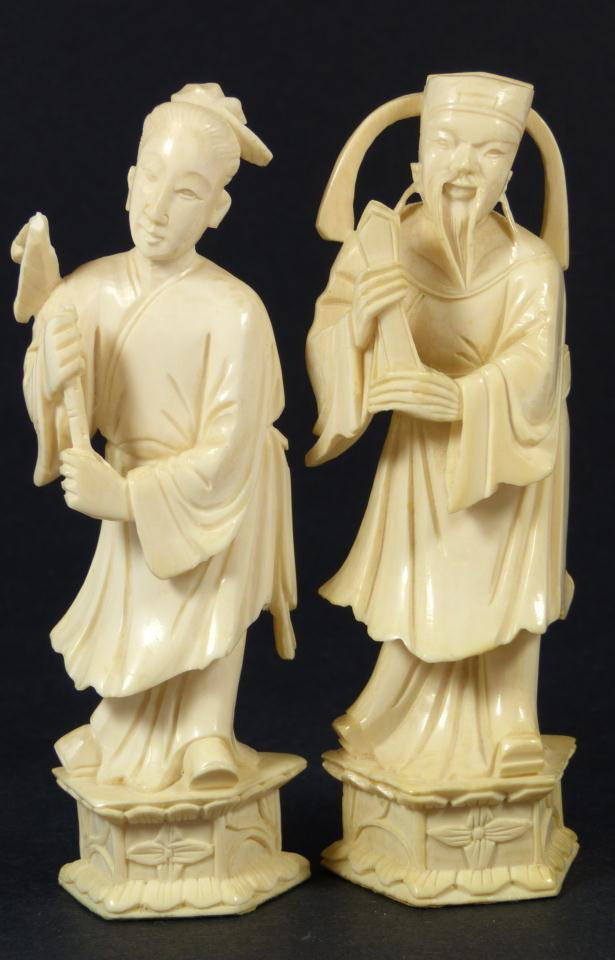 PAIR OF CHINESE CARVED IVORY NOBLE FIGURES: Pair of Chinese ivory figures depicting a bearded man with scepter. The other figure depicts a woman with layered robe. Figures are standing on a stylized lotus blossom base. Each is signed to the bac