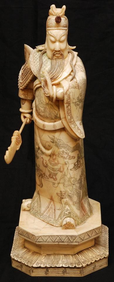 CHINESE CARVED & POLYCHROMED BONE WARRIOR FIGURE: Chinese hand carved polychromed bone warrior figure. He is holding a bladed spear with left hand to front. He is presented in layered robe with right arm and chest guard with intricate etched dragon d