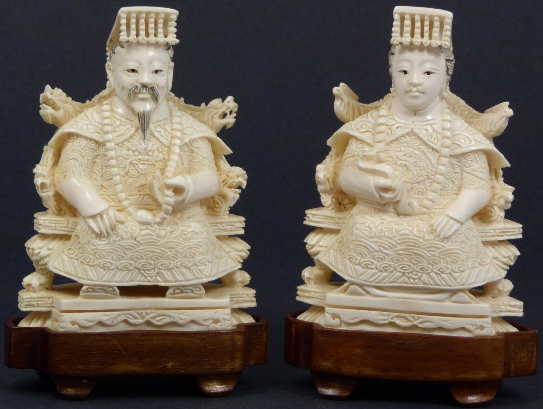 CHINESE CARVED IVORY EMPEROR & EMPRESS FIGURES: Chinese hand carved ivory Emperor and Empress figures. Each is depicted in a seated position on dragon and Pheonix throne. They are wearing Imperial beads and the Empress is holding a Ruyi scepter. In