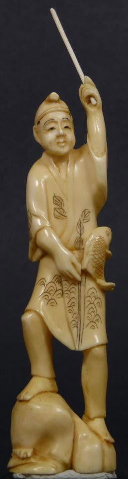JAPANESE CARVED IVORY FIGURE OF A MAN FISHING: Antique Japanese hand carved figure depicting a fisherman. He is holding a fishing pole in his left hand with fish at hip. He is standing on rocks. Etched designs to layered robe. 19th century. Includ