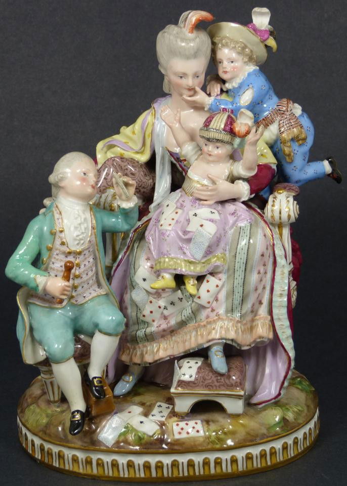 MEISSEN PORCELAIN GROUP OF MOTHER & 3 CHILDREN: Antique Meissen German porcelain group figure depicting a woman sitting in a seat with three children. The children are playing cards. Has blue crossed swords mark to bottom with the number 4. written