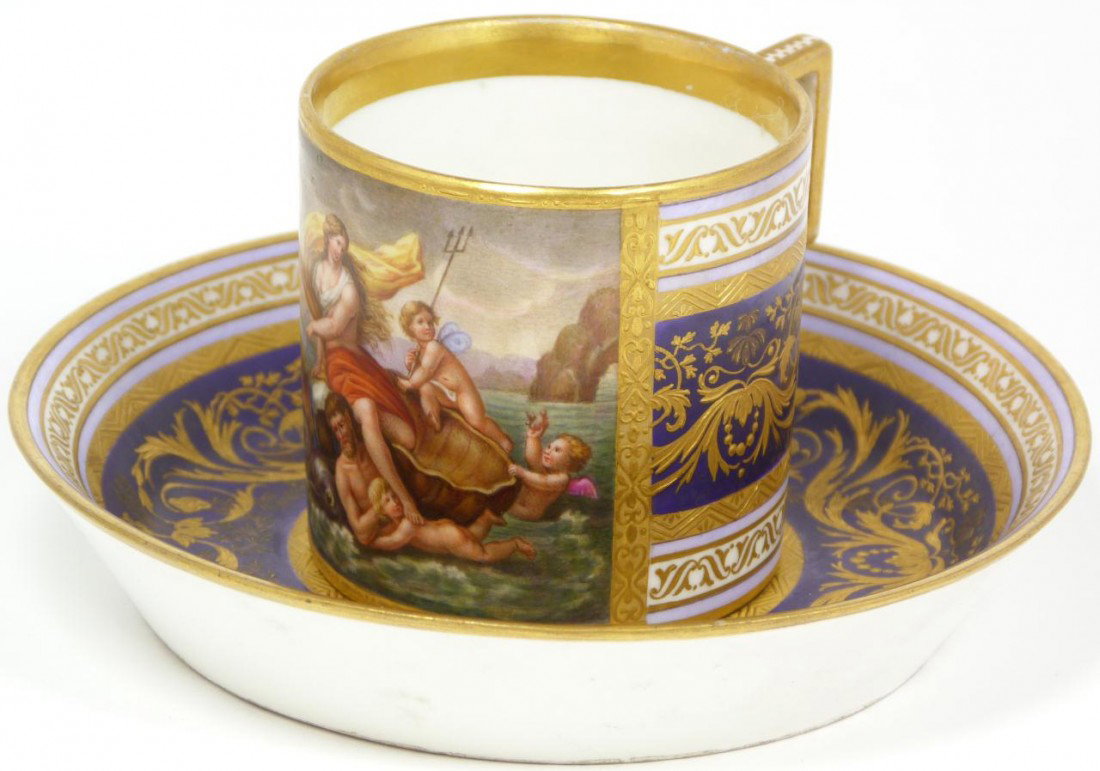 ROYAL VIENNA COBALT & GOLD PAINTED MUG & SAUCER: Antique hand painted Royal Vienna Austrian porcelain portrait cup and saucer set. Has scene depicting a nude female on shell being pulled by whales, mermen and cherubs. Stunning gilt work over purple,