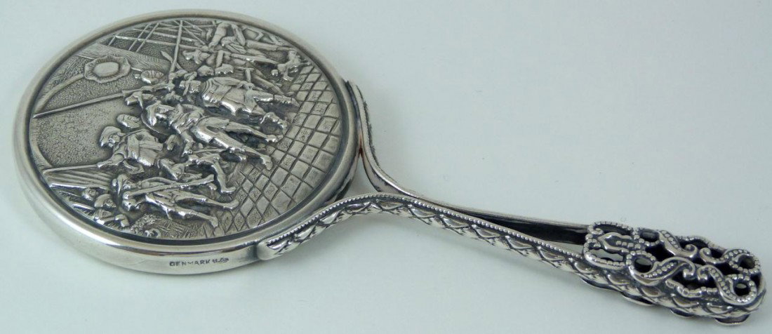 DANISH SILVER PLATE REPOUSSE HAND MIRROR: Antique Danish silver over copper repousse hand mirror. Has very detailed raised design to back of mirror depicting a fighting scene. Handle has a scrolled design. Beveled glass mirror. Marked Denmark