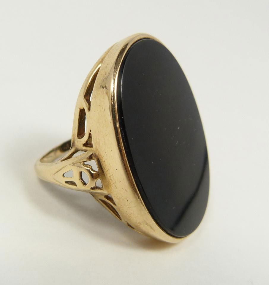 14KT YELLOW GOLD & ONYX DECO RING: 14k yellow gold and onyx ring. Has oval onyx set with pierced design to mounting. Ring size 7.25. Total weight of 6.8 dwt / 10.6 grams.