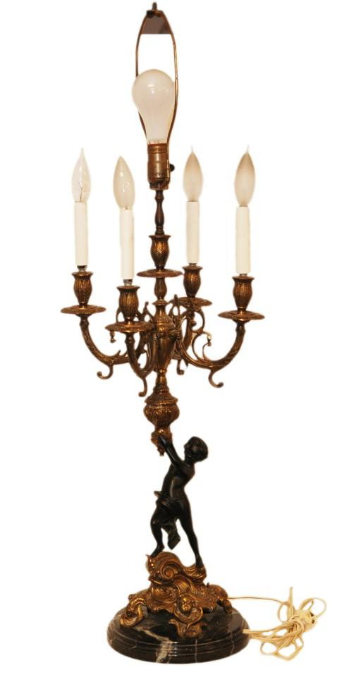 19th C. BRONZE CHERUB CANDELABRA LAMP ON MARBLE: 19th century bronze figural five arm bronze cherub candelabra. Depicts a cherub holding up an urn with the arms of the candelabra extending out. Has scroll design throughout. Beautiful black and gold 