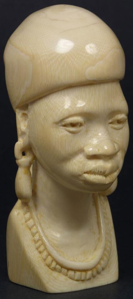 AFRICAN CARVED IVORY BUST OF NATIVE WOMAN: Hand carved African ivory bust figure. Depicts a tribal woman with headdress and long earrings. Measures 5 5/8" height (14.2cm).