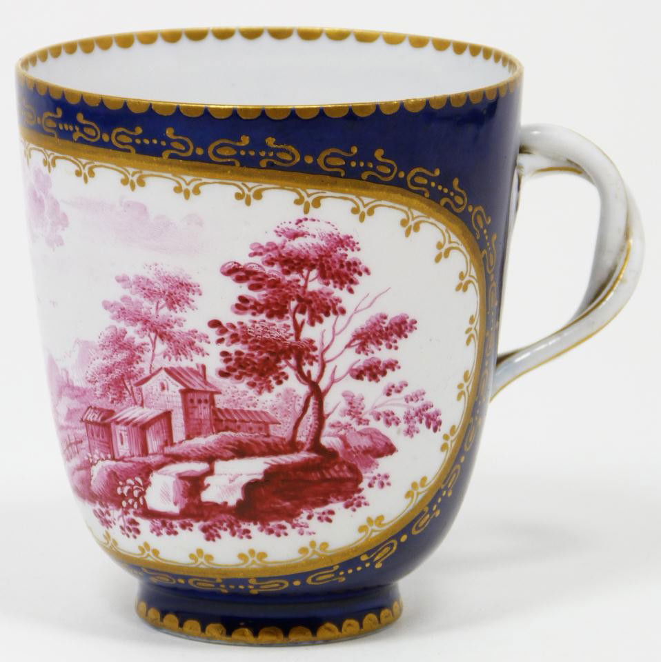 ANTIQUE EUROPEAN PORCELAIN HAND PAINTED TEA CUP: Antique European porcelain hand painted teacup. Has figural interlaced vine handle with hand painted enameled landscape scene to front of cup. Has gilded border design over cobalt blue background. Pro