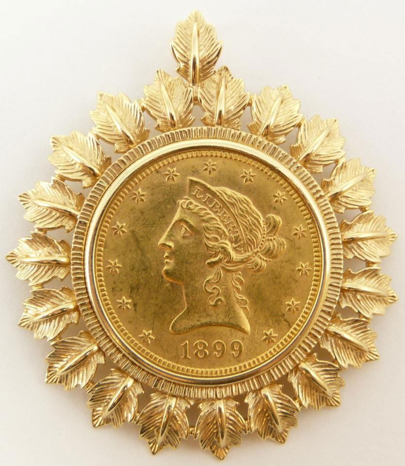 1899 $10 LIBERTY HEAD GOLD EAGLE COIN PENDANT: 1899 ten dollar Liberty Head gold eagle coin pendant. Has a figural leaf 18k yellow gold mounting. Measures 1 7/8" diameter (4.7cm). Total weight of 18.4 dwt / 28.7 grams.