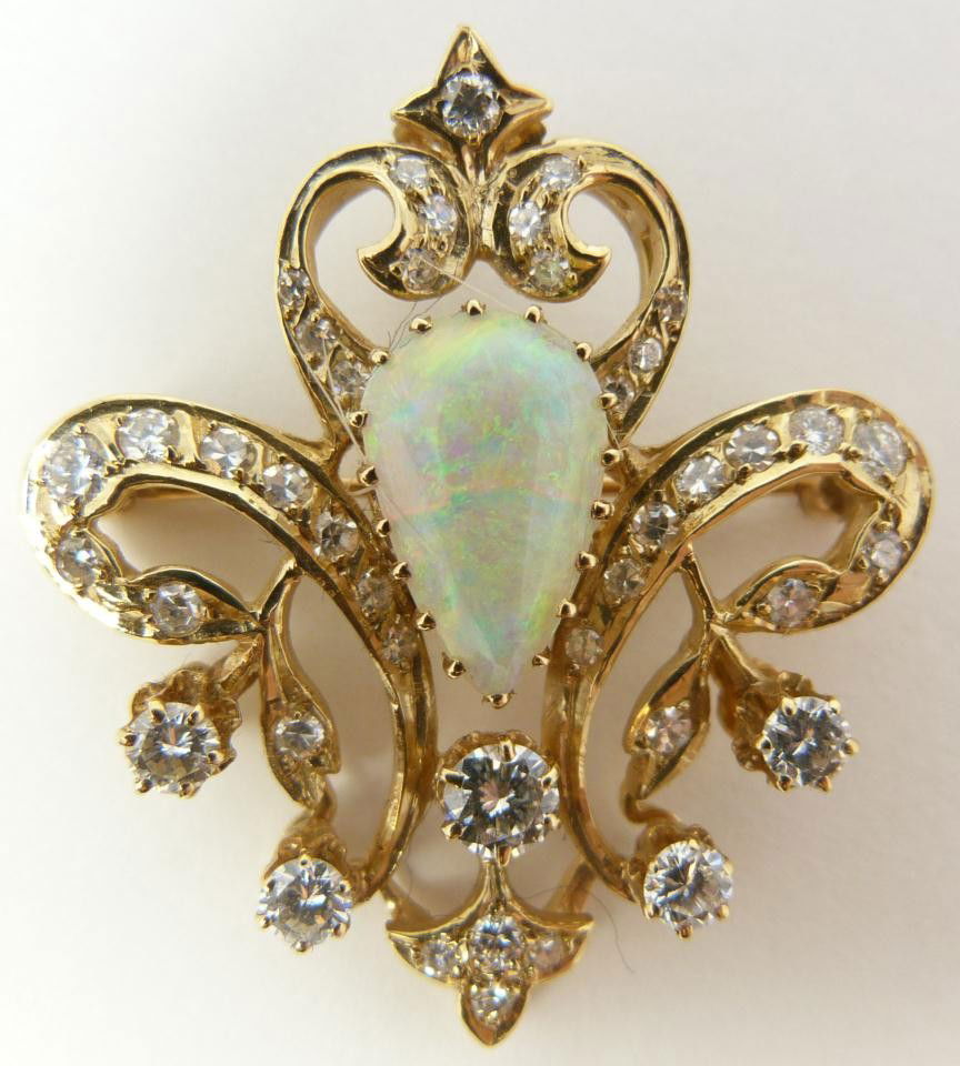 14KT YG DIAMOND & FIRE OPAL PENDANT BROOCH: Brilliant 14k yellow gold pendant holding a pear shaped fire opal mounted to center. Accenting the gold and opal is numerous round cut white diamonds. Stunning floral design with a fleur-de-lis shape.