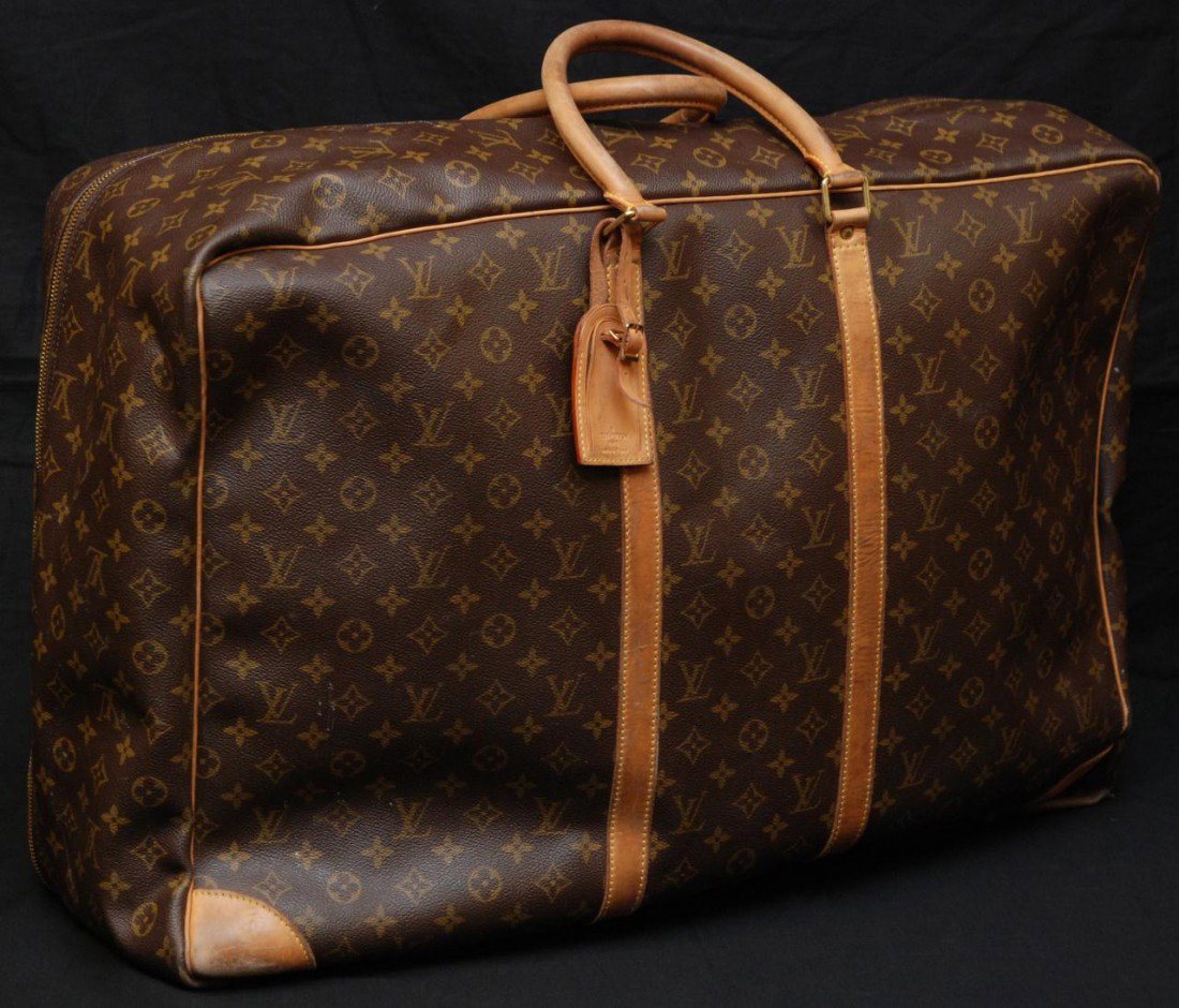 LOUIS VUITTON LEATHER GARMENT BAG: Original Louis Vuitton Sirius softside suitcase. Closes with a double zipper. It is easy to carry with its comfortable rounded handles and bears a removable ID holder. Monogram canvas, natural leather