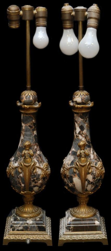 PAIR ANTIQUE MARBLE AND CHERUB ORMOLU LAMPS: Matching set of Italian black and white mottled marble lamps uniquely shaped in Italian design and fitted with fluting cherubs of brass draped and intertwined with naturalistic foliage. Each carved an
