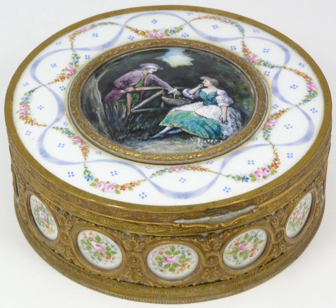 SEVRES FRENCH PORCELAIN ENAMEL SCENE BOX: Sevres antique French Porcelain hand painted round hinged box. Has a hand painted enamel on copper round plaque set to center depicting a courting couple. Has porcelain border with hand painted floral