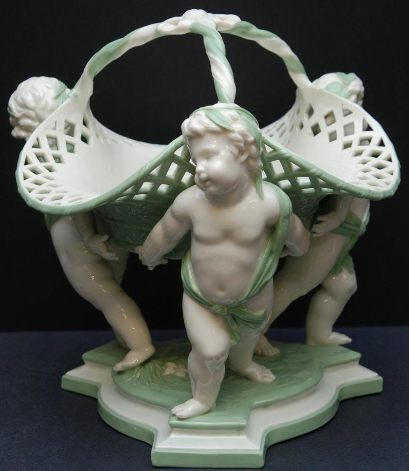 ANTIQUE MINTON ENGLISH PORCELAIN CHERUBS BASKET: Antique mid 19th century Minton English porcelain 3 cherubs basket. Basket has a reticulated design with three cherubs holding up the basket with three strand handle. Impressed Minton marks to bottom.