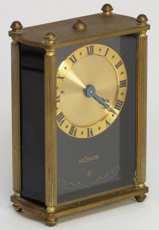 ANTIQUE LECOULTRE SWISS 8 DAY TRAVEL ALARM CLOCK: Antique Le Coultre 8 day travel alarm clock. Has black onyx front under glass screen. Gold face with metallic cobalt blue hour and minute hands. Has black enamel Roman Numerals. Black onyx side panels
