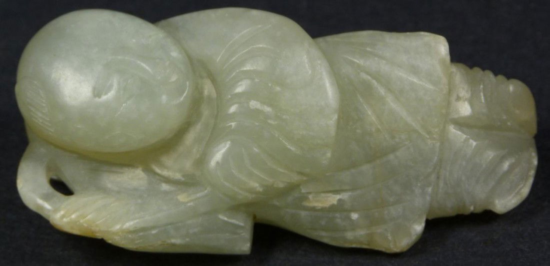 CHINESE CARVED JADE OKIMONO FIGURE OF WISE MAN: Chinese hand carved figure of wise man with lotus blossom. He is depicted in layered robe and looking to the ground. Measures 2 3/4" height (6.9cm). Total weight of 54.2 grams.