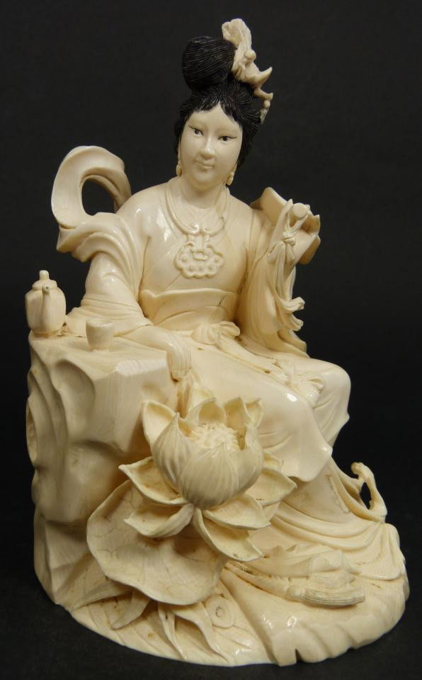 FINE CHINESE CARVED IVORY MAIDEN FIGURE: Magnificent Chinese hand carved elephant ivory figure depicting a seated maiden with paddle fan. In her hair is a Phoenix hairpin. She is sitting near rock with teapot and cup. At her feet is lily pad