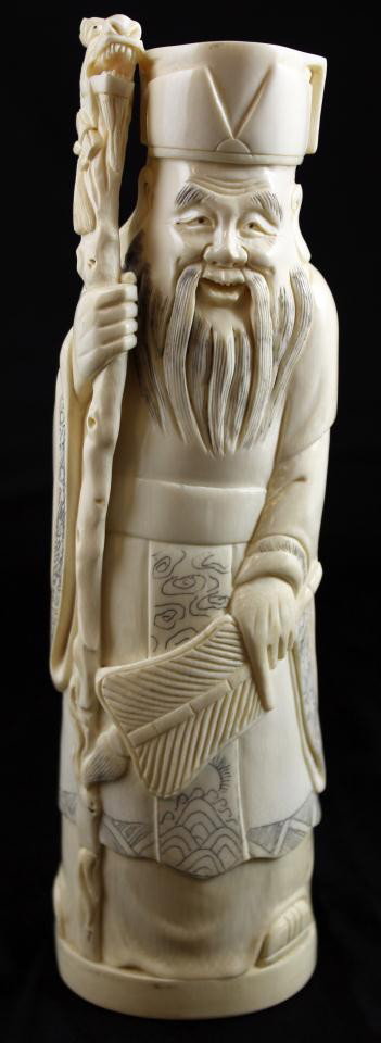 CHINESE CARVED IVORY FIGURE OF SHOU DEITY: Hand carved Chinese ivory figure depicting the Taoist deity of Longetivity and part of the "Three Lucky Stary Gods". The figure depicts the deity smiling with paddle fan pointed down and held in left 