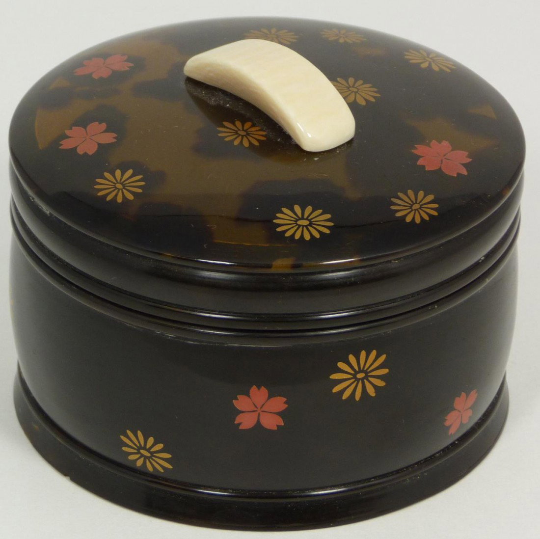 JAPANESE TORTOISE AND IVORY FLORAL ROUND BOX: Magnificently carved and polished round covered box constructed of tortoise and ivory. Has hand painted gold and red enamel flowers. Measures 2 3/4" height x 3 1/2" diameter (6.9cm x 8.9cm).