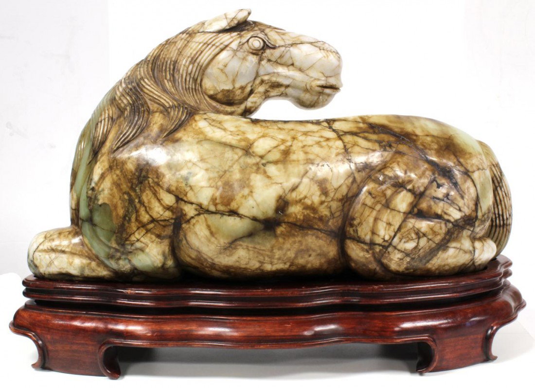 CHINESE HAN DYNASTY CELADON JADE HORSE FIGURE: Large hand carved celadon jade horse figure. Horse is finely carved and depicted in a recumbent position with head pointed back. Beautiful glowing pale apple green jade with russet. Includes fitted wo