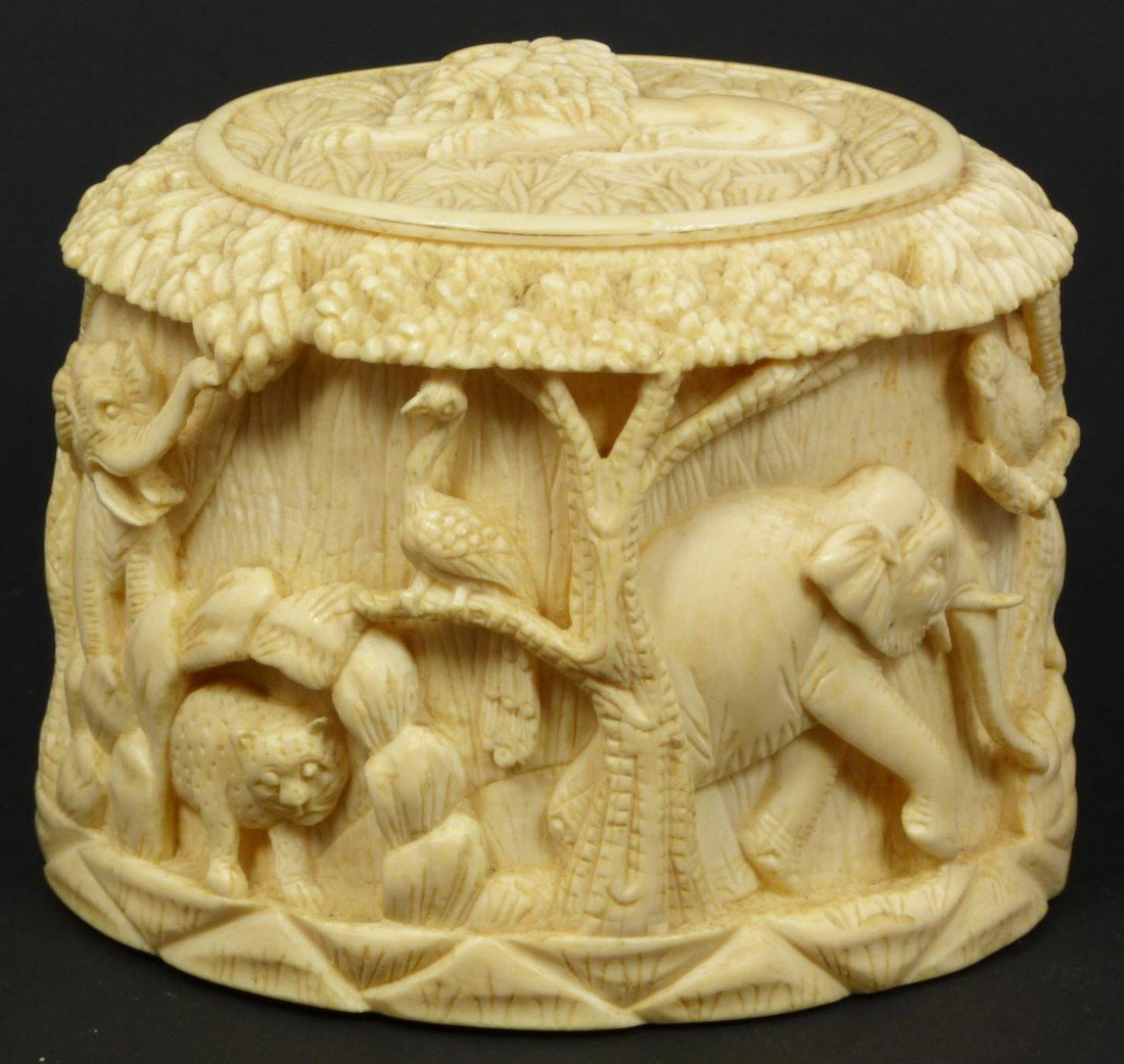 CHINESE RELIEF CARVED ANIMALS COVERED BOX: Chinese intricately carved ivory jungle scene box depicting elephants, birds, lions and cheetahs. Has recumbent lion to cover. Masterfully carved. Measures 3 3/8" height x 4" length x 3 1/4" depth (8.