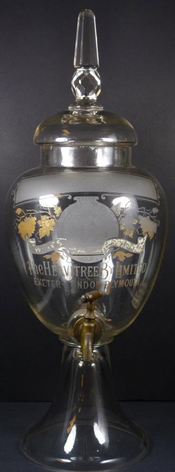 ANTIQUE ENGLISH ETCHED GLASS WINE DISPENSER: Antique English etched glass wine and spirits dispenser. Includes old copper spigot with cork. Has etched design to front with Heavitree by Limited trademark. Has rounded cover with spire to top. Meas