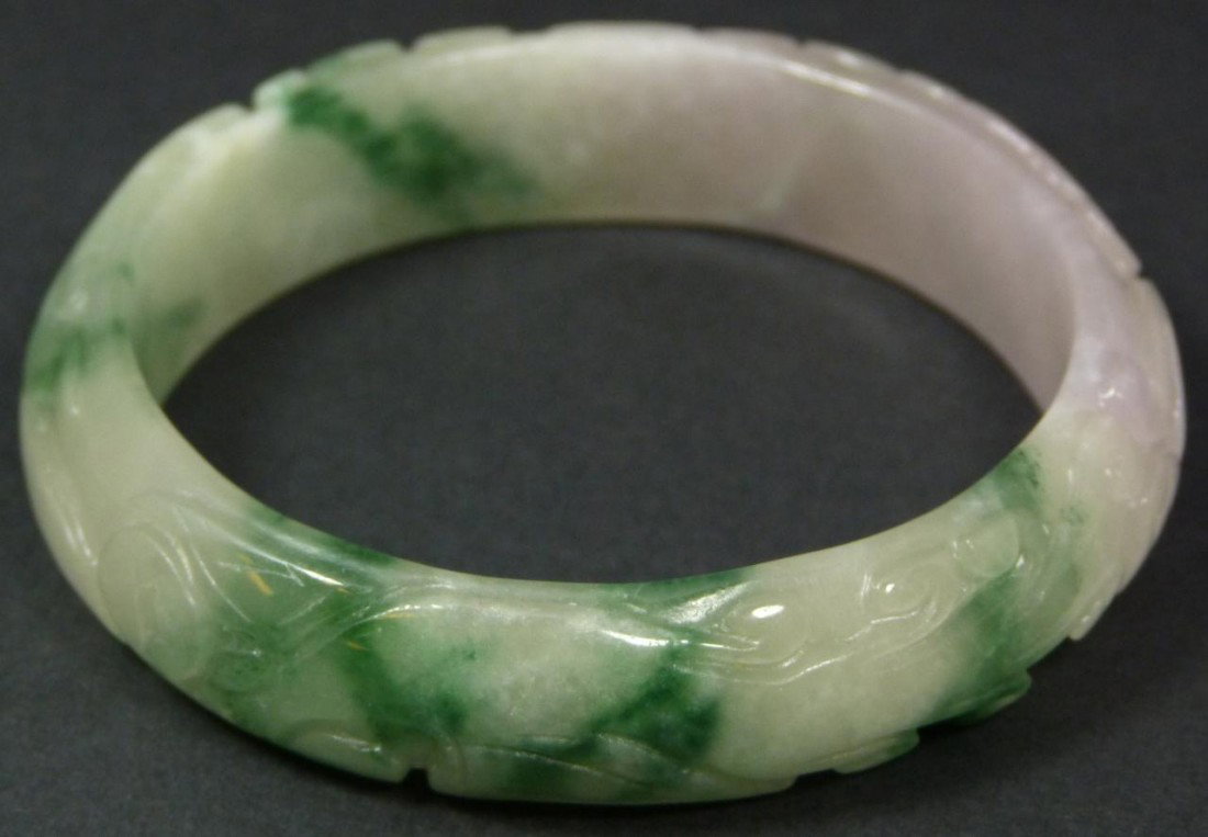 CHINESE RELIEF CARVED JADEITE BANGLE BRACELET: Relief carved Chinese jadeite bangle bracelet. Beautiful high quality mottled jade with white, apple green and hints of lavender colors. Measures 3 1/8" diameter (7.9cm). Fits wrist approximately 2 3/