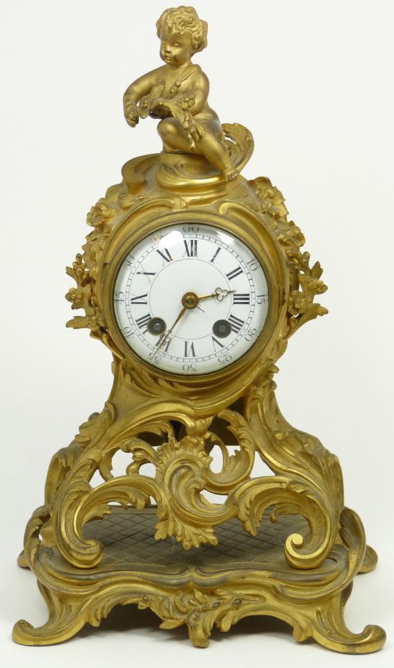 TIFFANY & CO LOUIS XV DORE BRONZE MANTLE CLOCK: Tiffany and Company, New York, 1875-1900. A Louis XV style dore bronze mantel clock, rococo style case cast with foliate scrolls and flowers, on scroll feet and surmounted by a cherub finial, chapter 