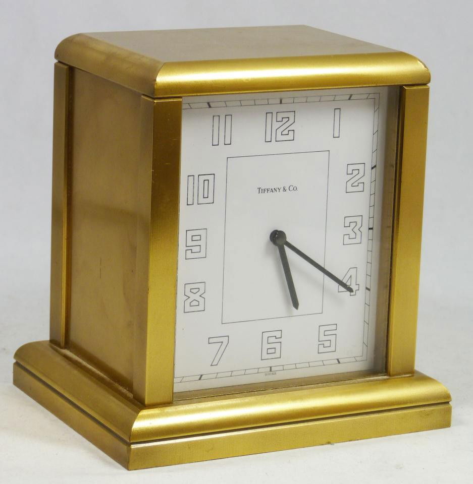 TIFFANY & Co VINTAGE BRASS MANTLE CLOCK 10298: Tiffany and Company Swiss brass mantle clock. Has a simple and elegant design with brass frame and white enamel face with black Arabic numerals. Has black hour and minute hands. Quartz movement. Marke