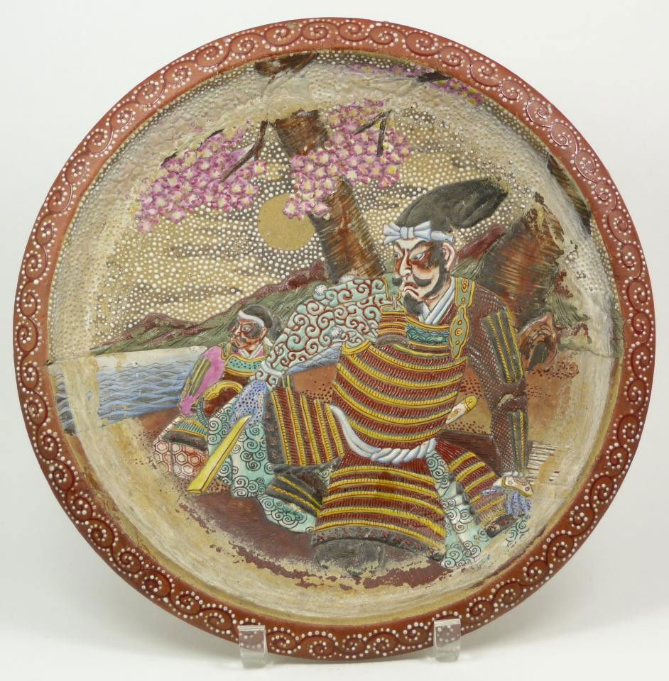 18th CENTURY SATSUMA EARTHENWARE SAMURAI CHARGER: Antique Japanese Satsuma Earthenware charger. Has vivid thick enamel design depicting two samurai resting under moonlight with seascape and mountains in the background. Enamel bead and swirl border. 1