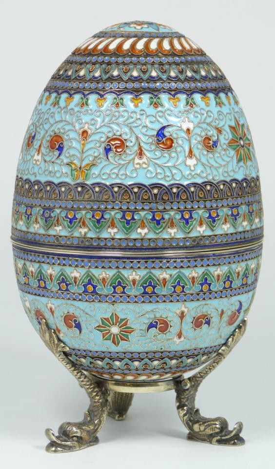 IMPERIAL RUSSIAN SILVER ENAMELED EGG: Russian silver enameled egg box having elegant scrolled design with pinwheels. Gold wash interior. Includes stand with three figural fish feet. Piece holds Cyrillic Pavel Akimov Ovchinnikov workmaster
