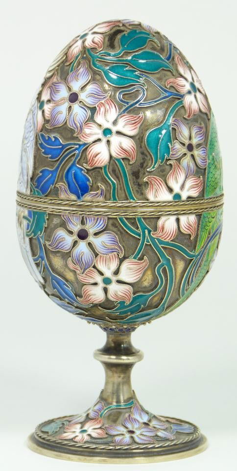 IMPERIAL RUSSIAN ENAMELED SILVER PARROTS EGG: Imperial Russian silver hinged egg having enameled design depicting flowers and birds. Gold wash interior. Holds town marks and 84 silver purity marks. Also holds Pavel Ochinnikov workmaster marks to