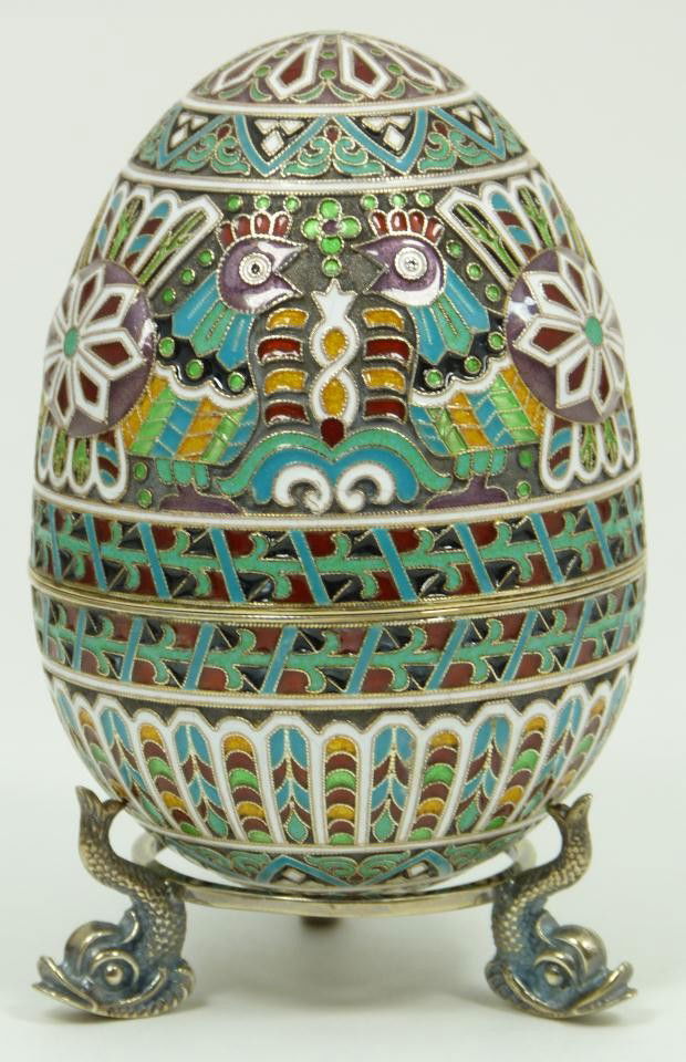 IMPERIAL RUSSIAN SILVER ENAMELED EGG OVCHINNIKOV: Russian silver enameled egg box having elegant scrolled design with chickens and pinwheels. Gold wash interior. Includes stand with three figural fish feet. Piece holds Cyrillic Pavel Akimov Ovchinnik