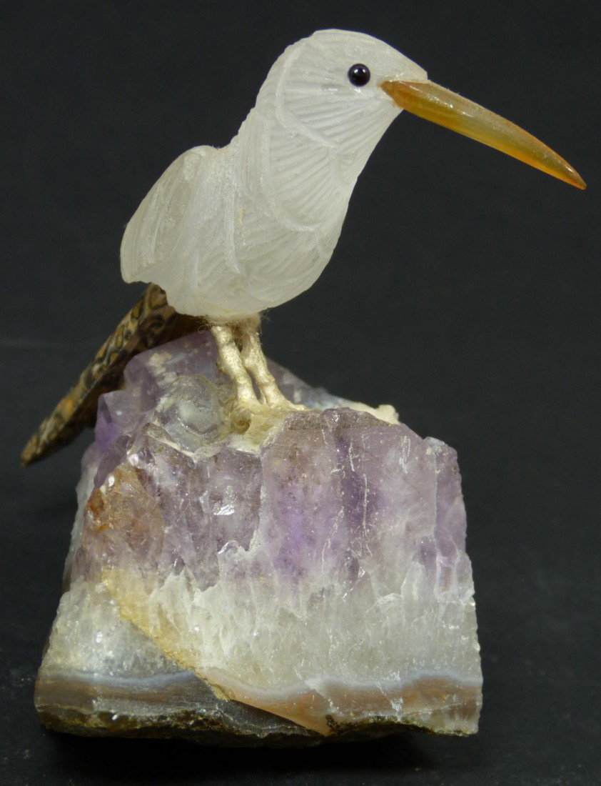 ROCK CRYSTAL BIRD ON AMETHYST ROCK: Hand crafted Rock crystal bird with agate beak and pudding stone tail feathers. He is standing on an amethyst rock base. Measures 3 1/2" height (8.9cm). Total weight of 175 grams.