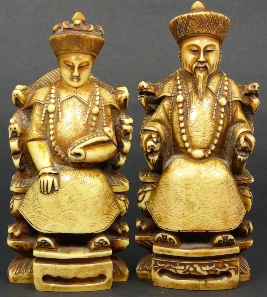 Pr CHINESE FAUX IVORY EMPEROR & EMPRESS FIGURES: Pair of Chinese hand carved faux Ivory Emperor and Empress figures. Each is depicted seated on throne in royal robe. The Empress is holding Ruyi Scepter in left hand with relief carved Phoenix robe an
