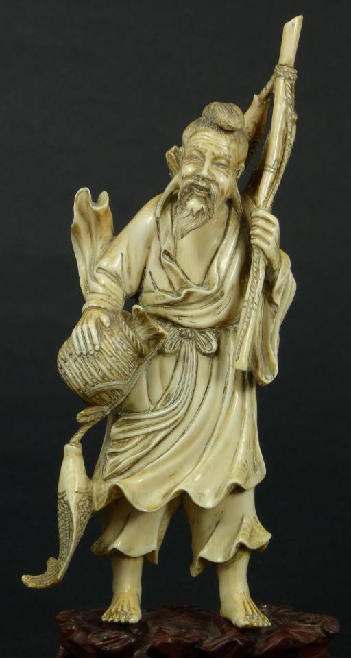 CHINESE CARVED IVORY FISHERMAN FIGURE: Antique Chinese hand carved ivory figure figure depicting am old fisherman holding a woven basket with fish to right hand. In his left is bamboo fishing pole with two fish. Signed to bottom of foot. 1