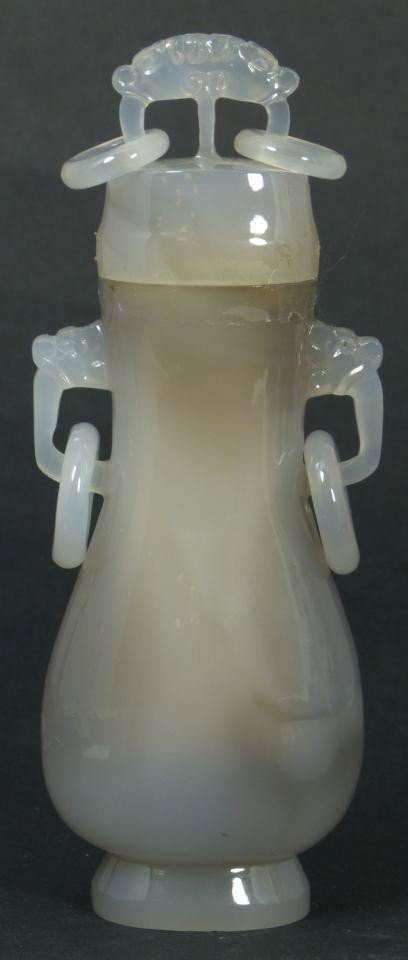 CHINESE HAND CARVED AGATE LIDDED VESSEL: Chinese hand carved agate lidded vessel having two handles to body with relief rings. Top has handle with two relief rings. Raised dragon design to front. Measures 5 1/2" height (13.9cm). Total weight