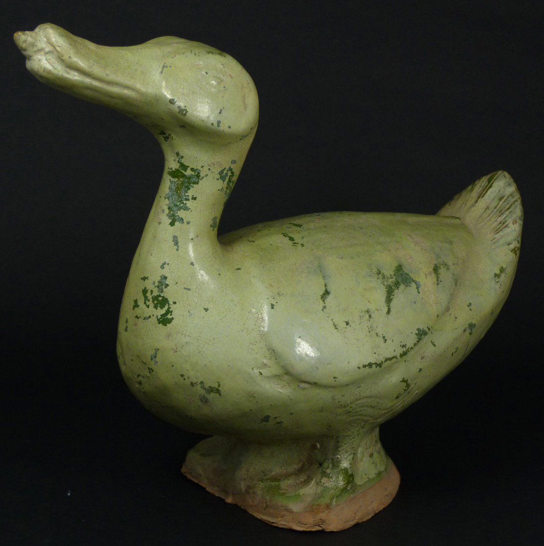 HAN DYNASTY CHINESE POTTERY FIGURE OF A DUCK: A pottery figure of a duck with slender, curved neck and upright head. Glazed with a fine crackle green coloration. Dating from the Han dynasty (206BC-220AD) 12” x 5” x 9 ½” (30.48cm x 12.7cm x