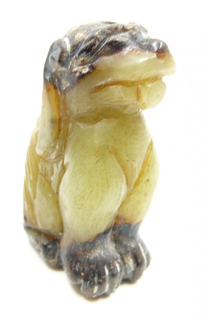 HAN DYNASTY CHINESE CARVED JADE FOO DOG: Han Dynasty Chinese hand carved jade seated foo dog. Finely etched and detailed throughout. Pale green to deep russet jade coloring. Measures 1 7/8" height (4.7cm). Total weight of 43 grams.