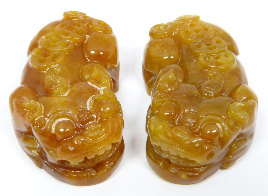 Pr OF CHINESE RUSSET JADE FOO DOG PENDANTS: Pair of Chinese carved russet brown jade pendants depicting foo dogs with coins. 20th century. Each measures approx. 1 3/4" length x 1" width (4.4cm x 2.5cm). Total weight of 50 gams.