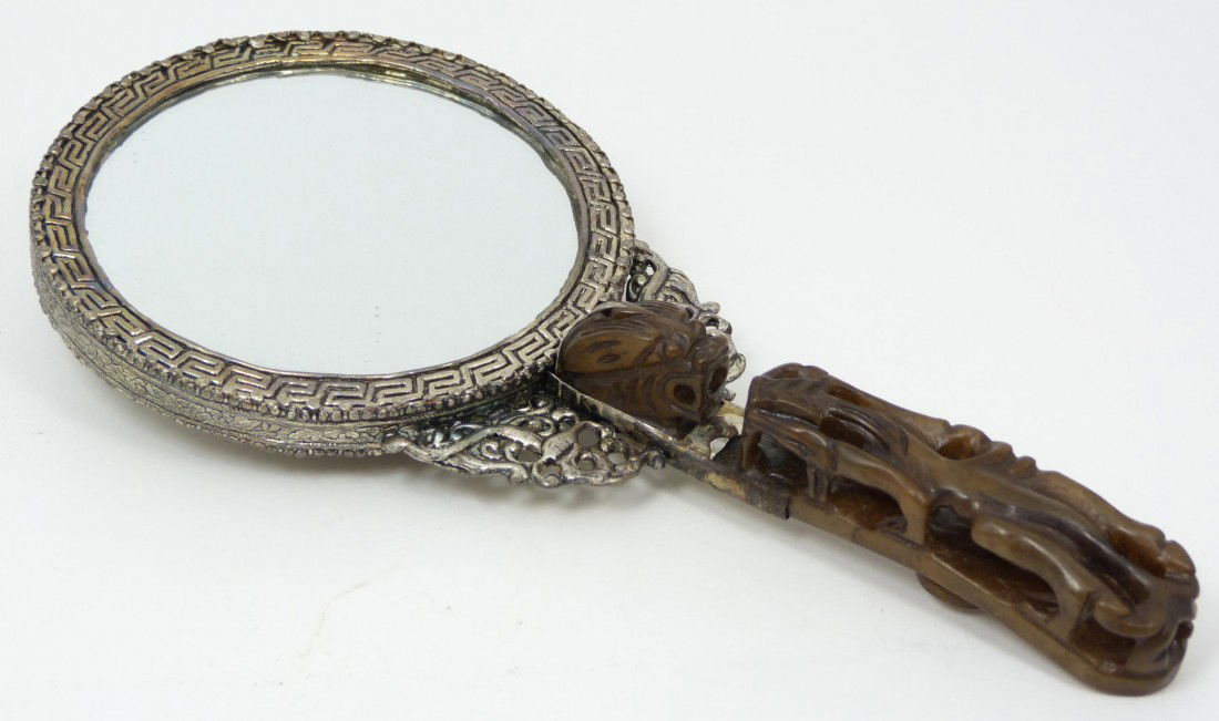 CHINESE SILVERED COPPER MIRROW w JADE HANDLE: Chinese silvered copper mirror with russet brown jade chih lung ruyi garment hook. Has a fabulous repousse dragon design with Etruscan bordering to back of mirror. Holds two cabochon cut agate stones
