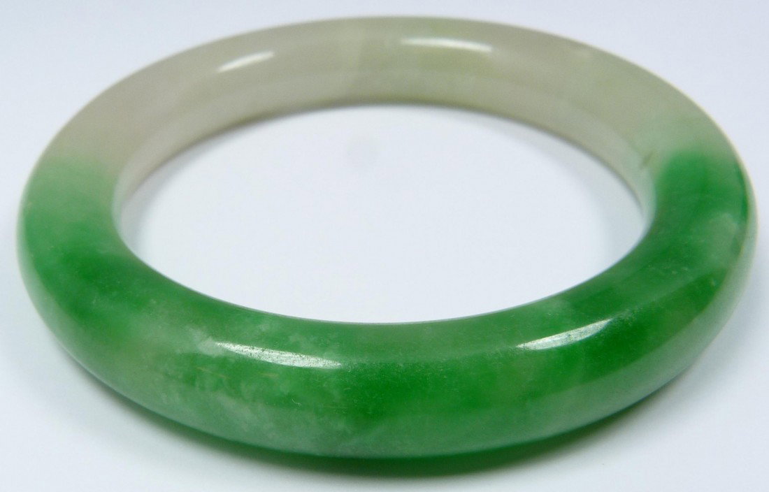 CHINESE CARVED JADEITE BANGLE BRACELET: Hand carved Chinese jadeite bangle bracelet. Beautiful translucent white and apple green mottled jade. Measures 3 3/8" diameter (8.5cm). Fits wrist approximately 2 3/8" diameter (6cm). Total jadeite w