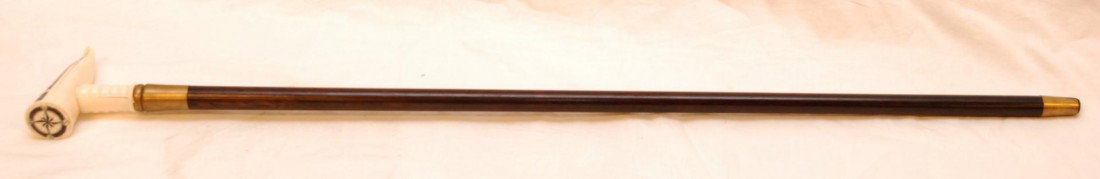 WALKING CANE WITH SCRIMSHAWED TOOTH HANDLE: Cane with scrimshawed tooth handle with compass and scene depicting a ship with whale and lighthouse. Measures 35 3/4" length (90.8cm).