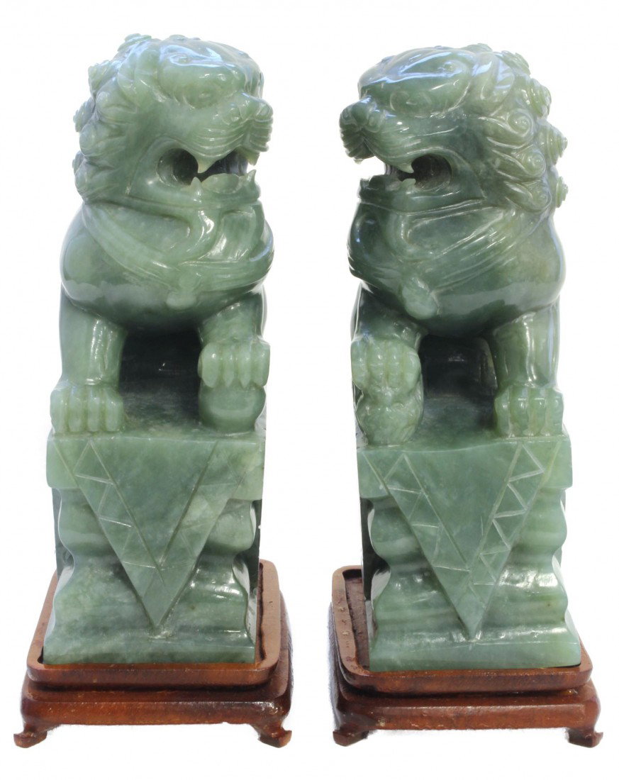 Pr OF CHINESE HAND CARVED JADE FOO DOG SCULPTURES: Pair of Chinese hand carved green jade foo dog sculptures. Each depicting a foo dog on a pedestal. One having a ball underfoot and the other a youngling. Includes fitted wooden bases. Beauctiful trans