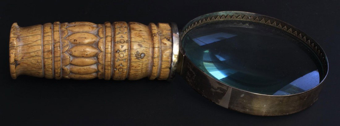 CARVED MAMMOTH IVOR HANDLED MAGNIFYING GLASS: Relief carved mammoth ivory handled magnifying glass with sterling frame. Has relief carved ribbed design to handle. Signed to frame "J. Amy 80 925". Measures 8 1/2" height x 4" width (21.6cm x 10.2cm
