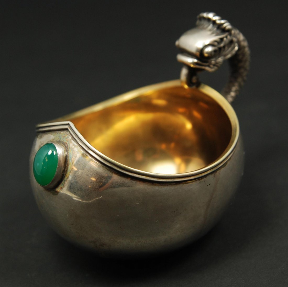 RUSSIAN SILVER KOVSH WITH GREEN CABOCHON STONE: Imperial Russian silver Kovsh having Faberge with double headed eagle marks. Handle has a figural fish handle design. Oval Cabochon green stone bezel set to front of vessel. Gold wash interior. Also h