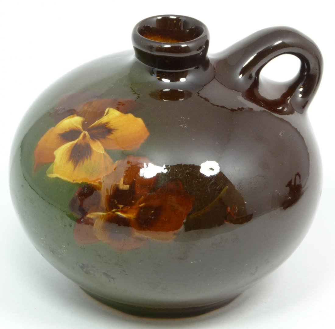 WELLER LOUWELSA BROWN GLAZE HANDHELD VESSEL: Weller Louwelsa handheld vessel having hand painted floral design over deep brown and green glaze ground. Late 19th century. Holds impressed maker's mark to bottom with 88. Measures 4 1/2" height x 5"