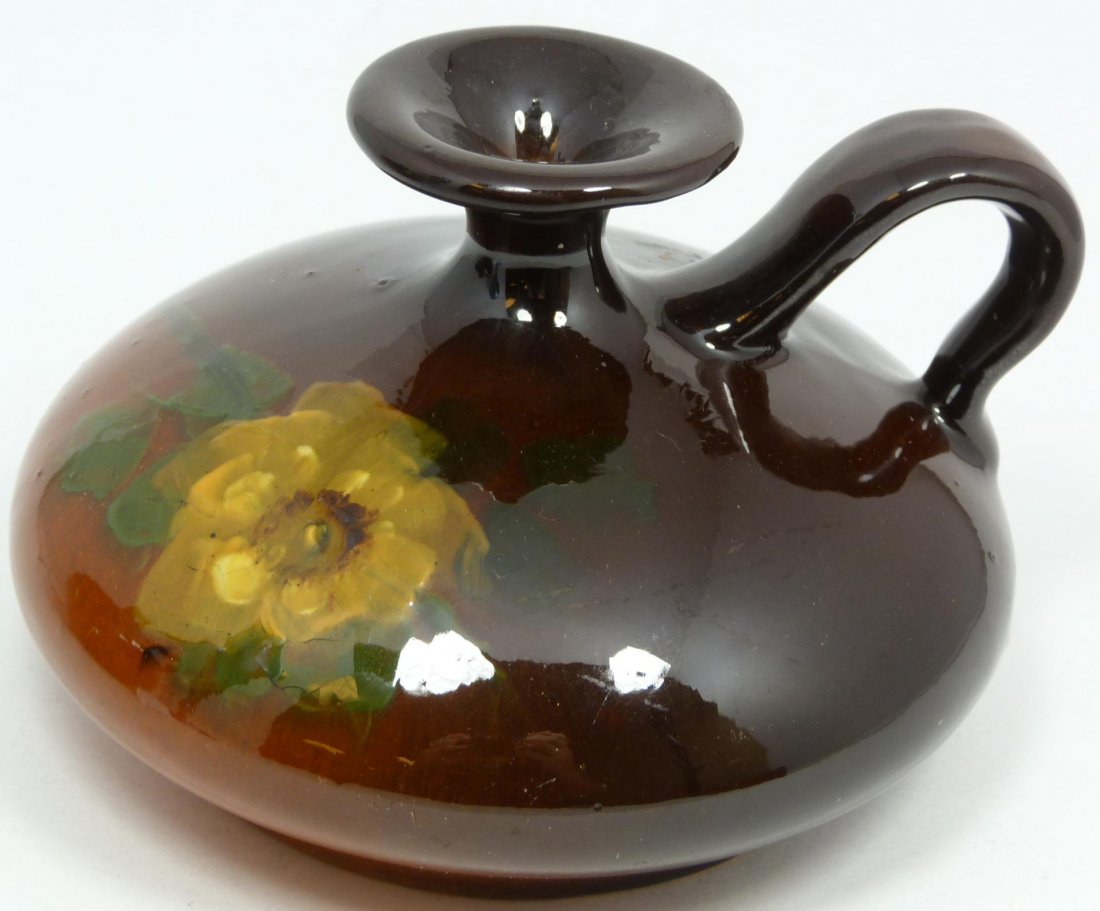 WELLER LOUWELSA BROWN GLAZE HANDHELD VESSEL: Weller Louwelsa handheld vessel having hand painted floral design over deep brown and orange glaze ground. Late 19th century. Holds impressed maker's mark to bottom. Measures 3 1/4" height x 4 3/4" di