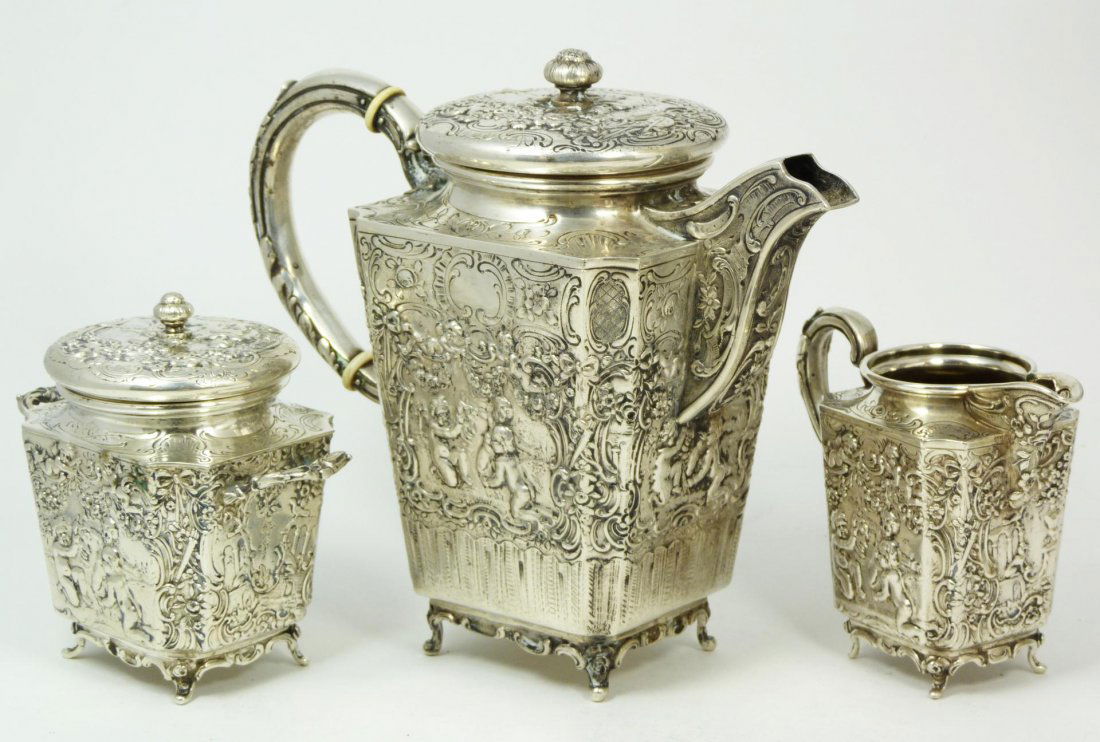 18th CENTURY GERMAN 800 SILVER REPOUSSE TEA SET: 3 piece Antique German 800 silver tea set having a stunning repousse design depicting cherubs and scrolled designs throughout. Each marked Germany 800 to bottom and holds town with maker's marks. Late