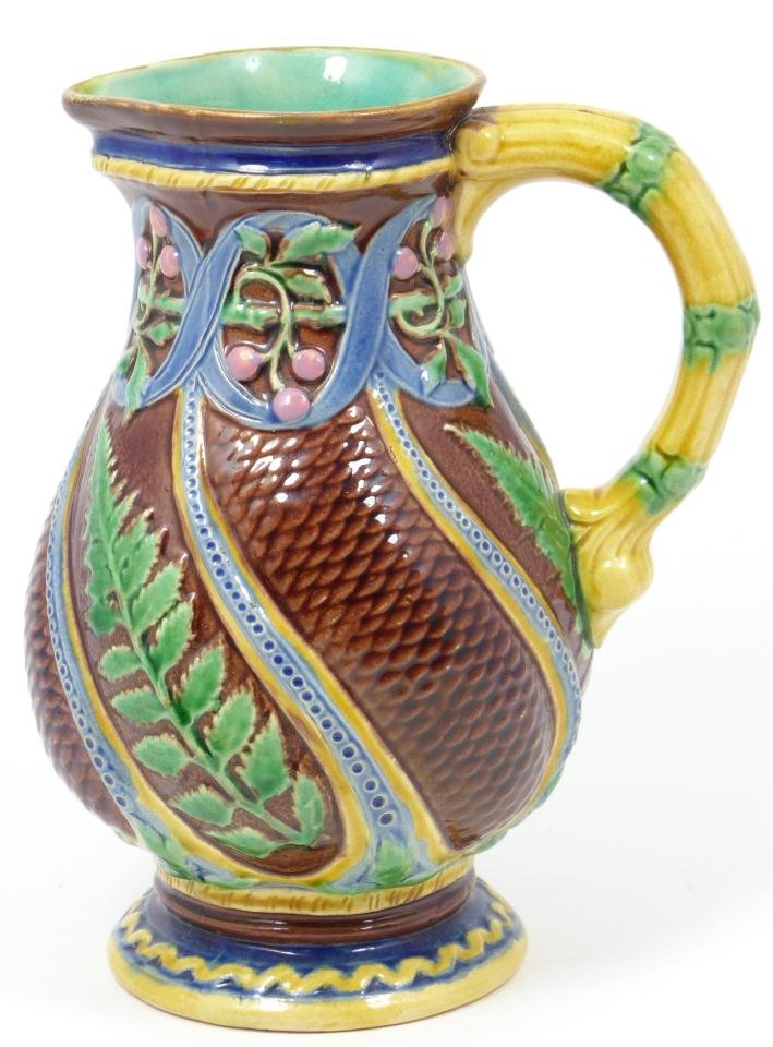 MINTON MAJOLICA FISH SCALE PITCHER: Minton English Majolica pitcher. Has tree and fish scale swirl design with raised floral decoration. Holds impressed Minton mark with raised registration mark to bottom. Also holds impressed 473 30. 1